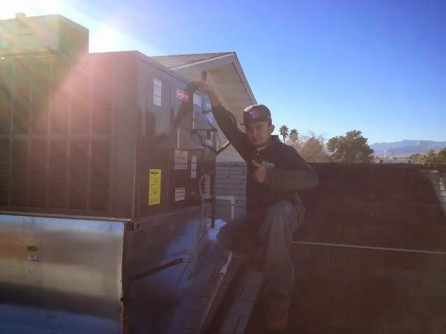 HVAC technician performing AC Tune-Up on a rooftop unit in Muskego